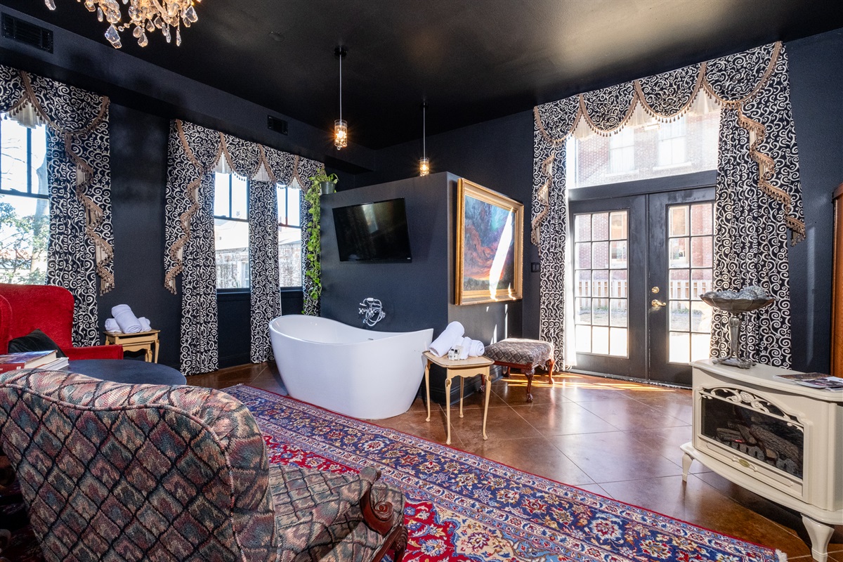 The Pagoda Suite interior featuring dramatic dark walls, freestanding soaking tub, and tall windows.