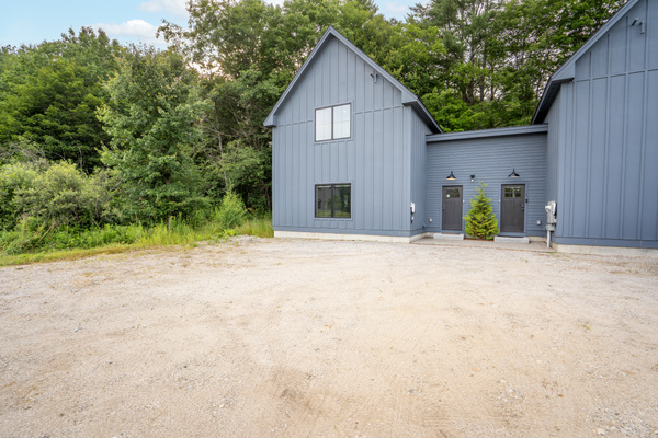 A welcoming exterior with convenient parking and a private setting surrounded by nature.