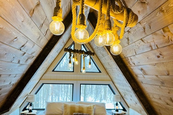 This dreamy second-story loft is accessible only by a ship’s ladder, adding an adventurous yet intimate feel. It features a king bed beneath a dramatic A-frame ceiling. Large triangular windows offer stunning views, making it the perfect hideaway.