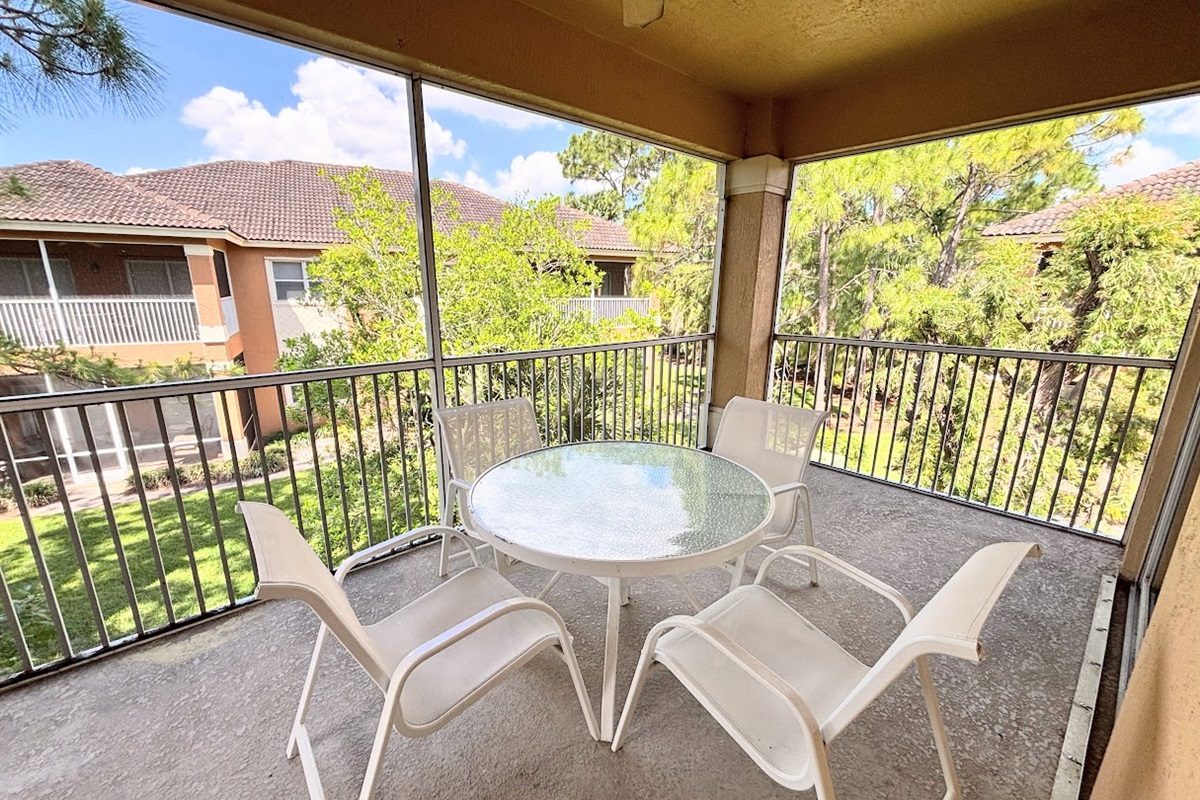 Private screened balcony with outdoor seating, offering a peaceful spot to relax and enjoy the surrounding greenery.