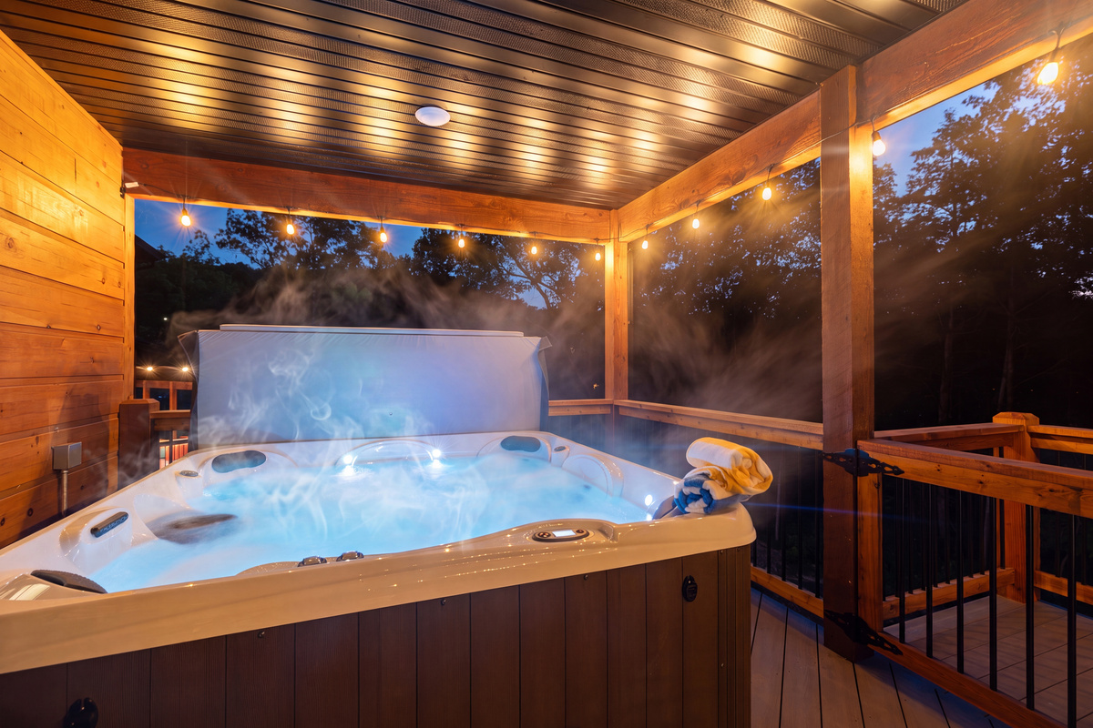 The hot tub glows blue against the dark treeline.