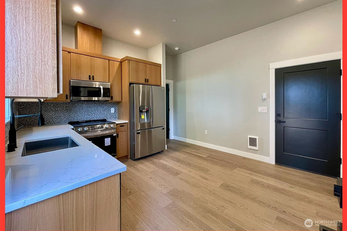 A sleek range and a generous quartz peninsula open to the living space — cook, sip and socialize without leaving the party.