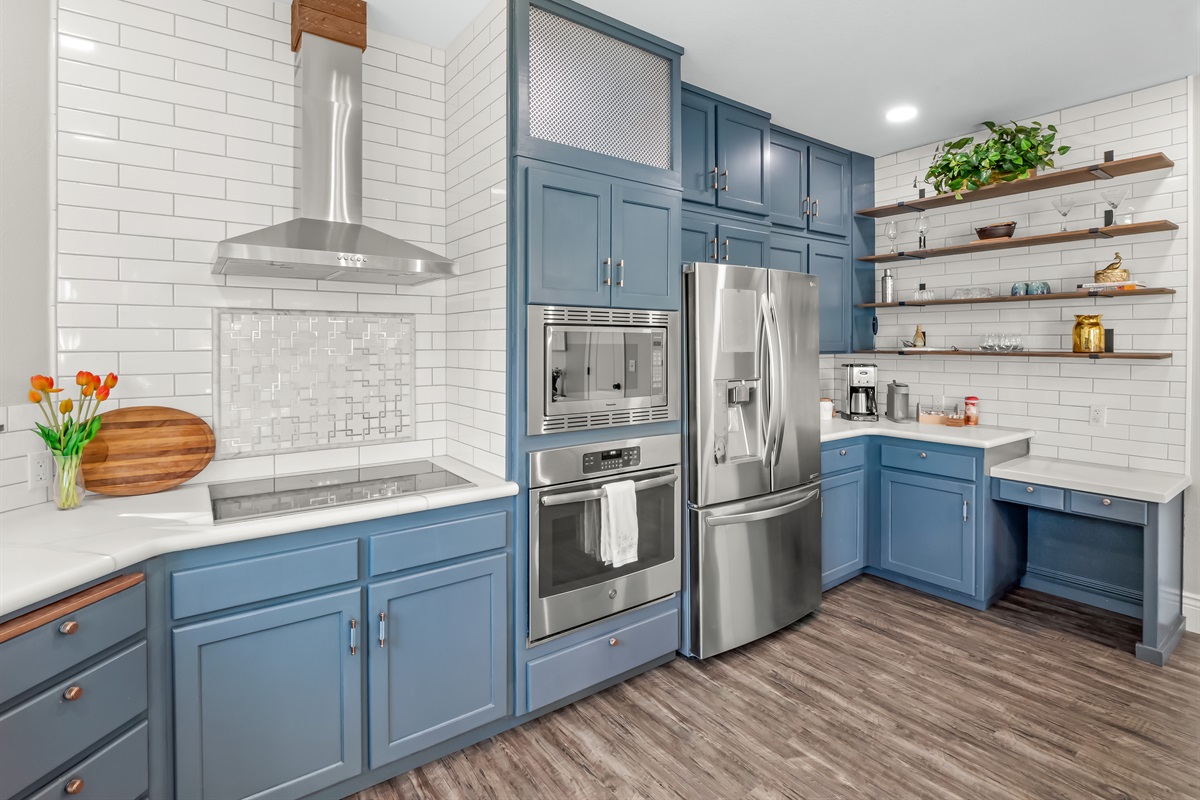 Modern chef’s kitchen featuring custom cabinetry, sleek stainless appliances, designer tile backsplash, and open shelving—an inviting space designed for effortless entertaining and elevated vacation living.