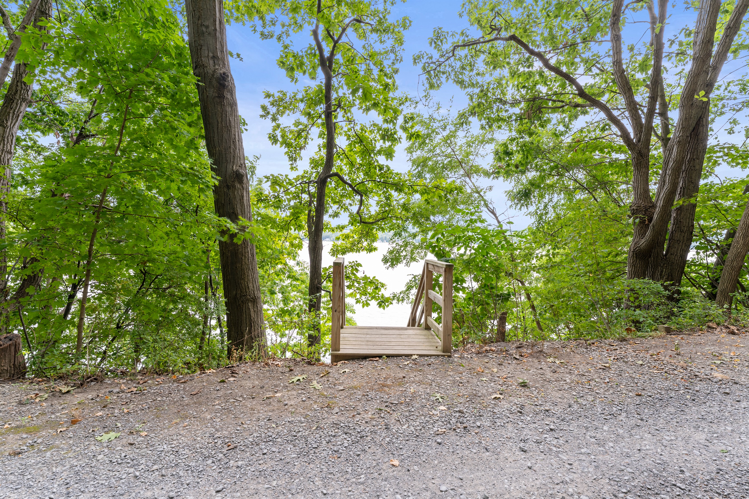 A charming woodland entrance guides you down to the sparkling lake, blending nature with relaxation.
