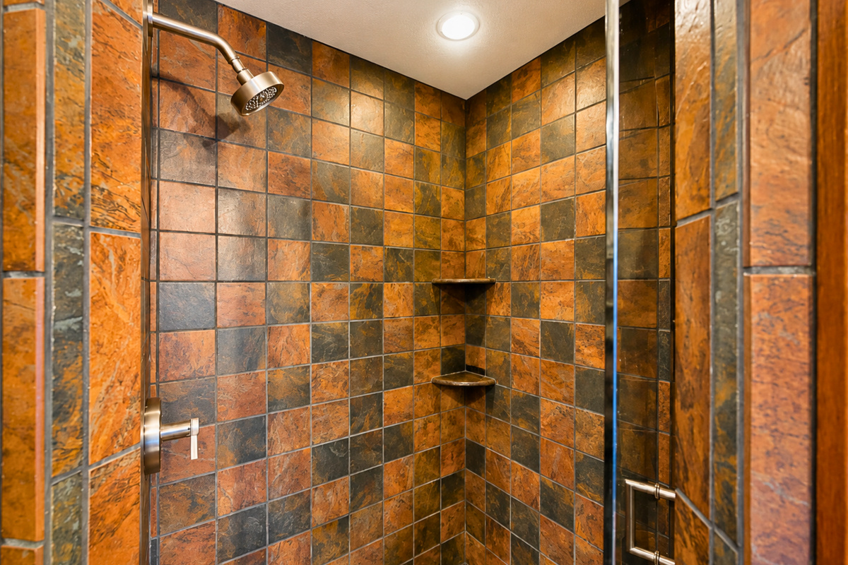 The walk-in shower is finished with richly colored tile that adds a rustic touch while keeping the space comfortable and practical.