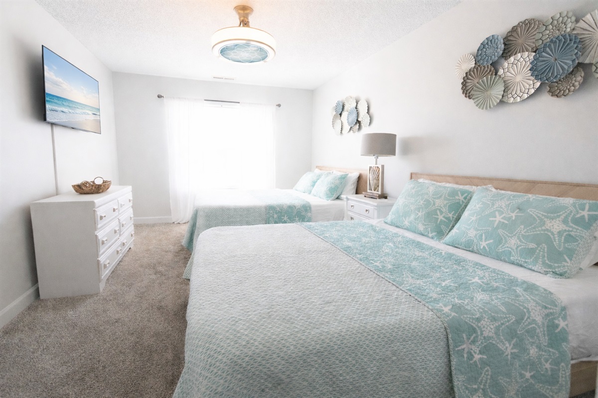 Soft coastal vibes and sweet dreams! Two comfy queen beds, beachy tones and a tv to wind down after a sunny day by the beach