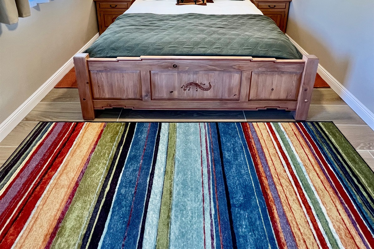 Unwind in the spacious bedroom, featuring a plush King-sized bed, a wall-mounted TV, and warm, rustic-style furnishings.