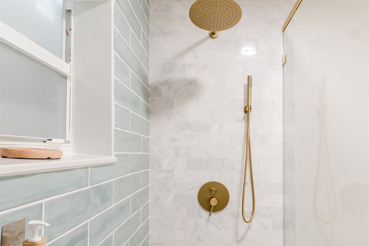 Spa-inspired ensuite with a walk-in glass shower, soft sage tile, and brushed brass fixtures. 