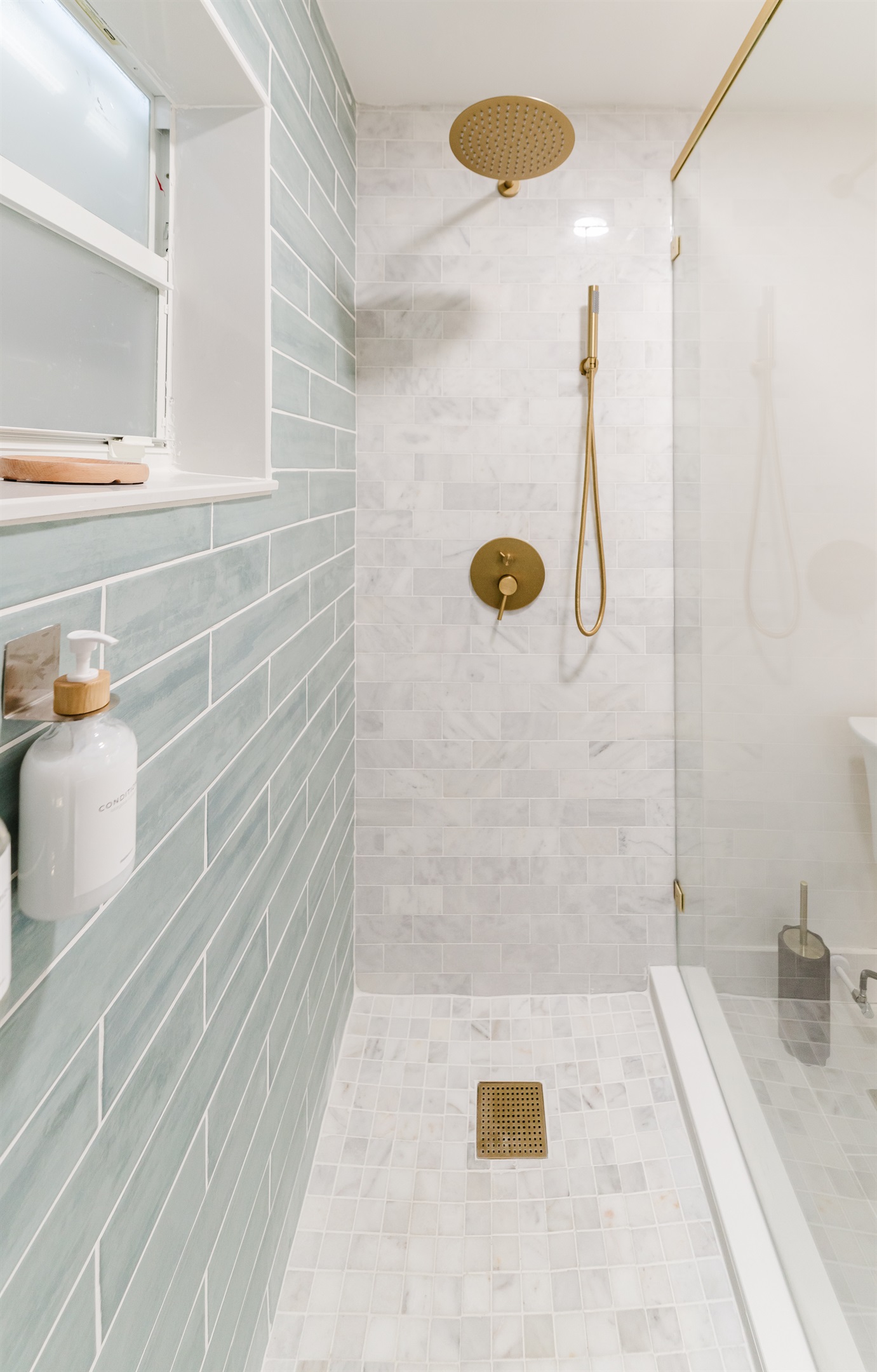 Spa-inspired ensuite with a walk-in glass shower, soft sage tile, and brushed brass fixtures. 