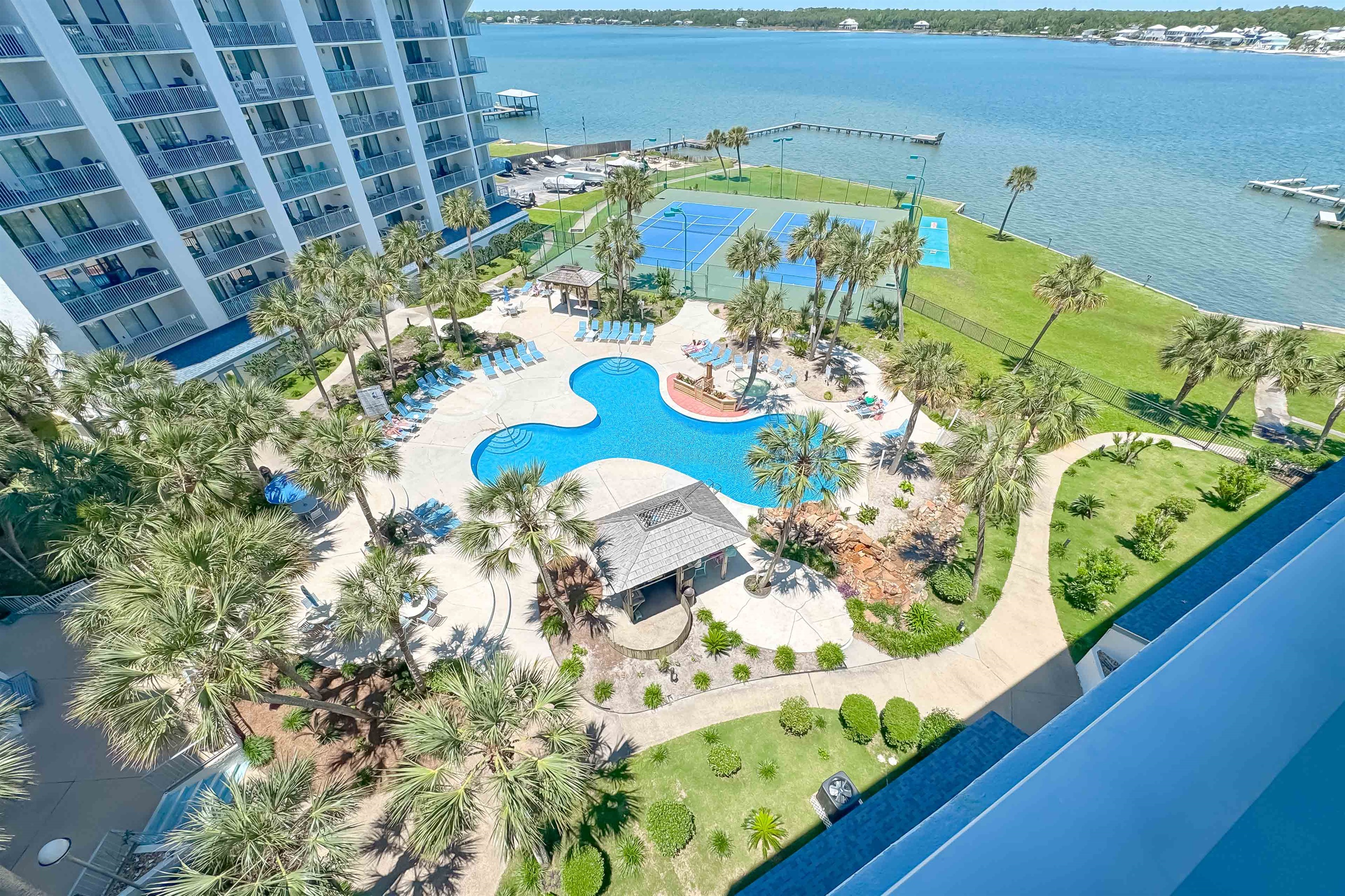A tranquil waterside escape awaits. This inviting pool and patio area, complete with comfortable loungers and dining tables, offers the perfect spot to relax and soak in stunning views of the bay.