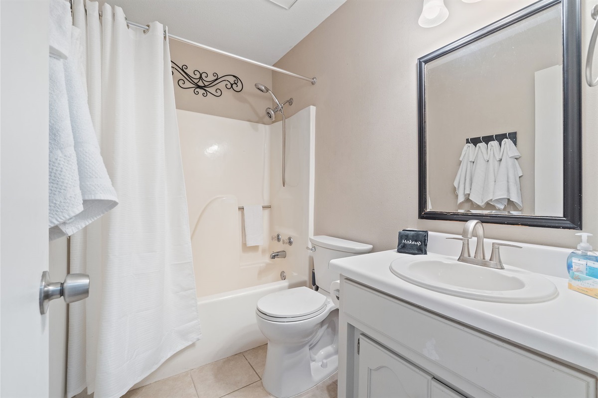 Enjoy a relaxing soak or a quick shower in this full bathroom equipped with a tub/shower combo, elegant vanity, and warm lighting. Thoughtful touches like rolled towels and decor make it feel just like home.