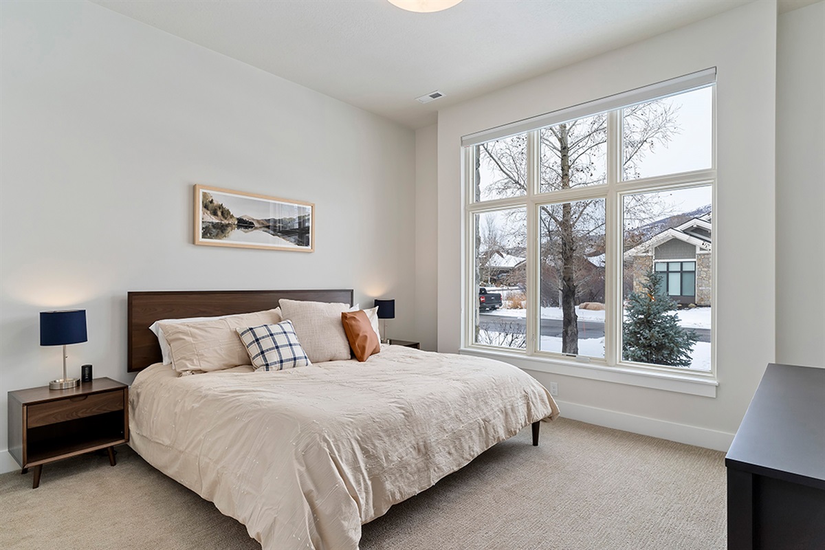 A cozy guest bedroom with soft natural light and a calming, neutral design.