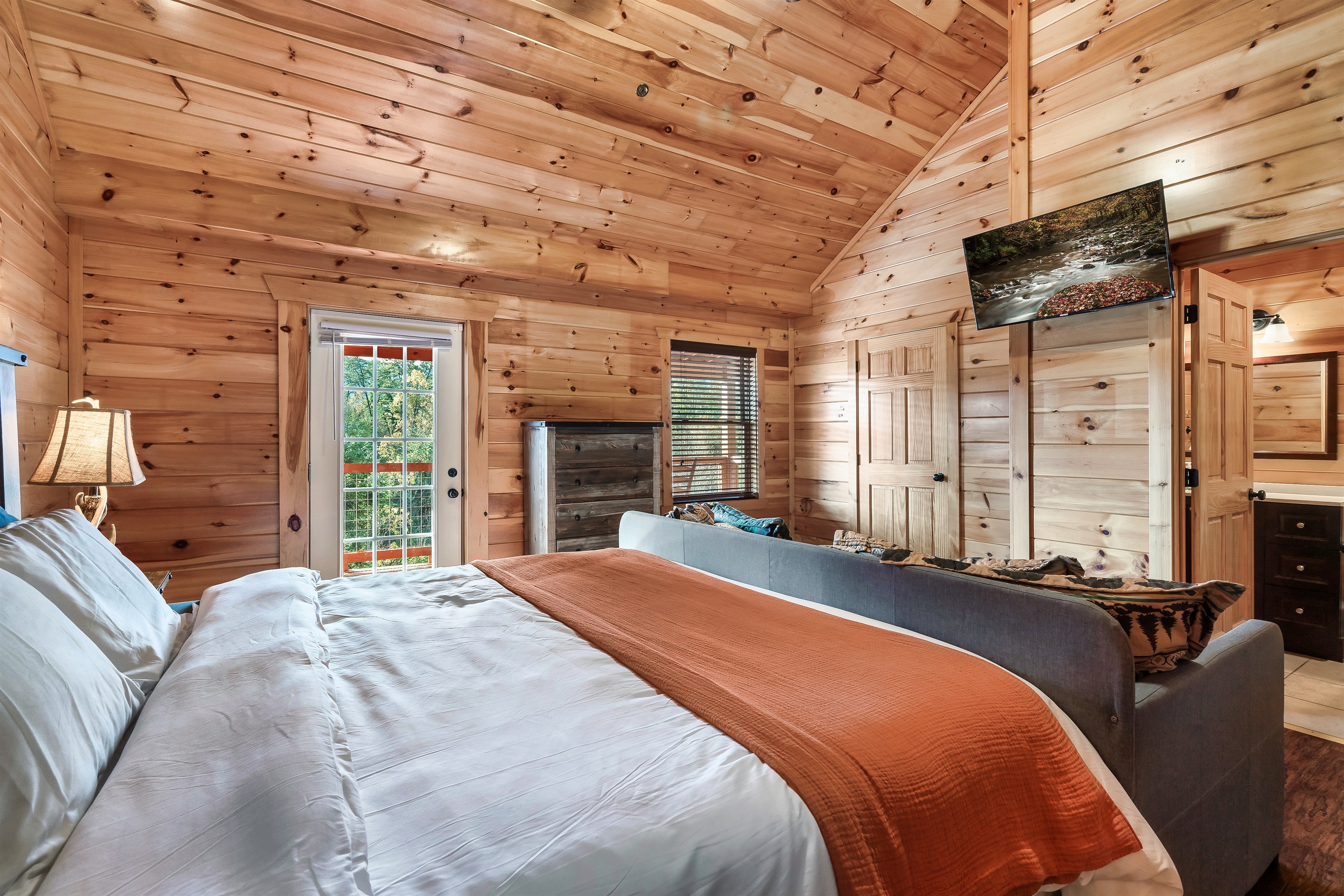 Stretch out in a spacious cabin suite where rustic charm, soft light, and balcony access elevate your stay.