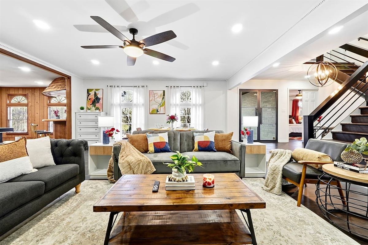 Warm and welcoming living room with two comfortable couches, two chairs, indoor plants, a cozy fireplace, and a TV powered by Google TV. Conveniently located as you walk through the front door and straight ahead from the primary side entrance. 