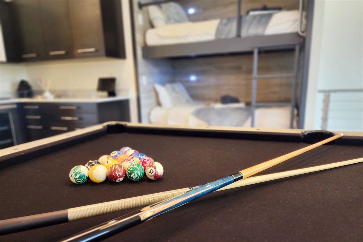 Pool table with beverage center and bunks in same room.