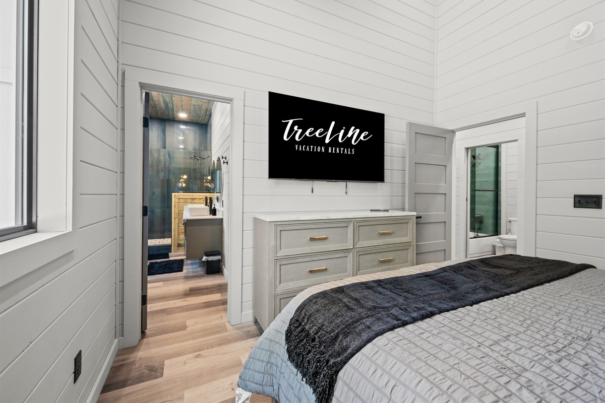 Natural light pours through the large window, highlighting the clean, modern design and relaxing feel of this spacious bedroom.