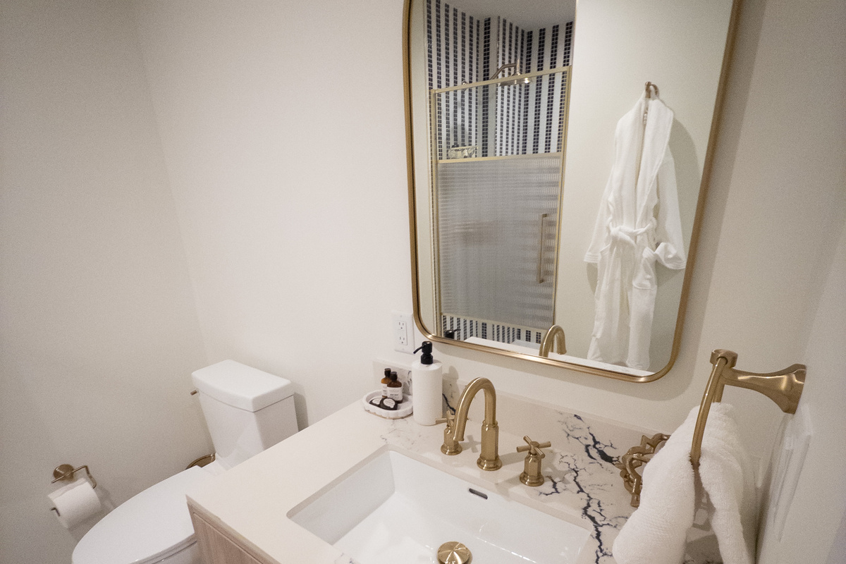 Walk-in rainfall shower behind frameless glass, with a plush robe waiting.