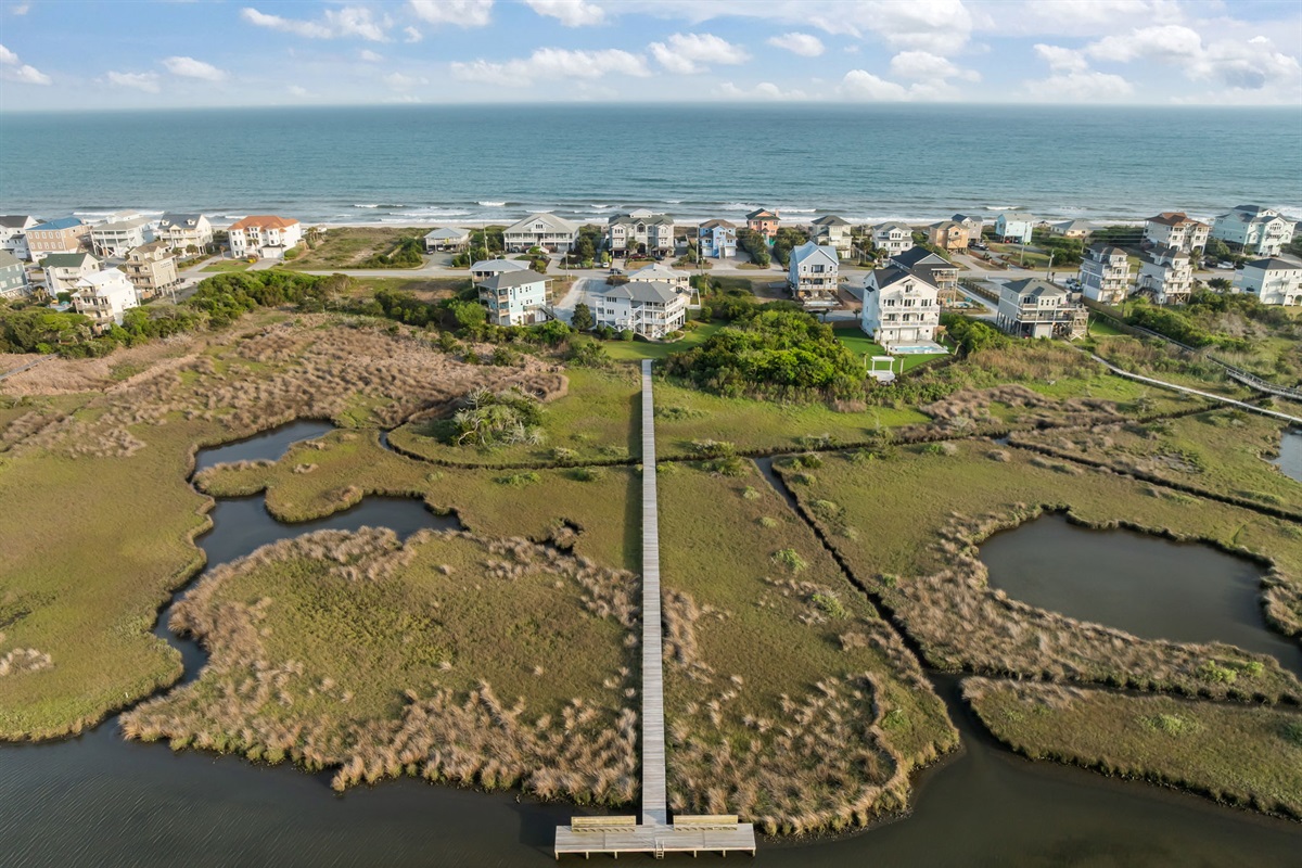 Scenic boardwalk stretching from the home to the water with ocean just beyond