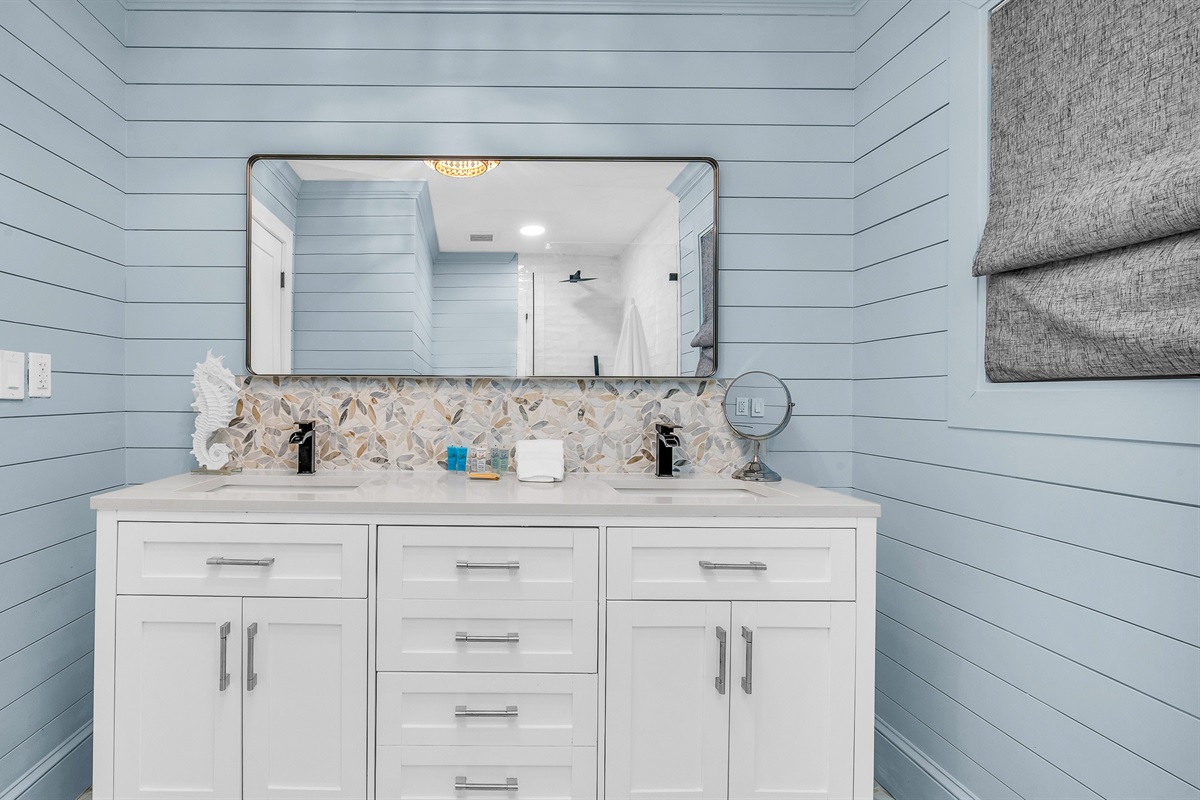 Primary Bathroom: This spa-inspired bathroom features sleek coastal design with a walk-in glass shower, modern fixtures and soft natural light- creating a serene retreat for relaxation and rejuvenation
