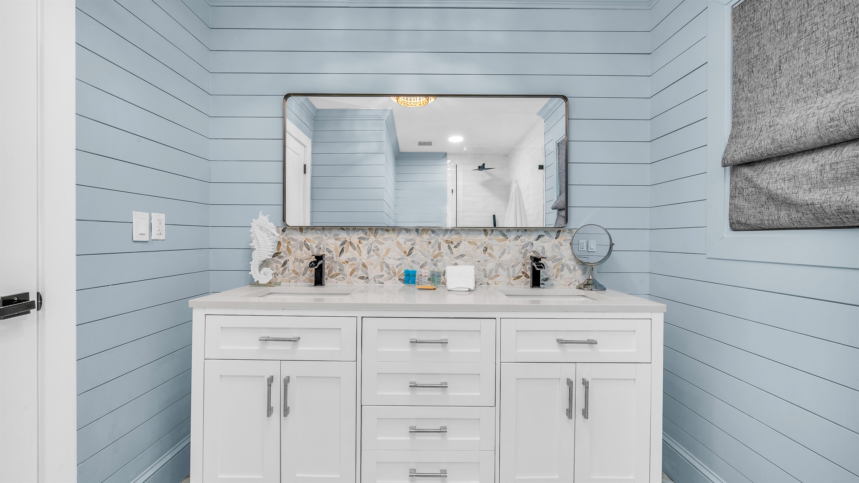 Primary Bathroom: This spa-inspired bathroom features sleek coastal design with a walk-in glass shower, modern fixtures and soft natural light- creating a serene retreat for relaxation and rejuvenation