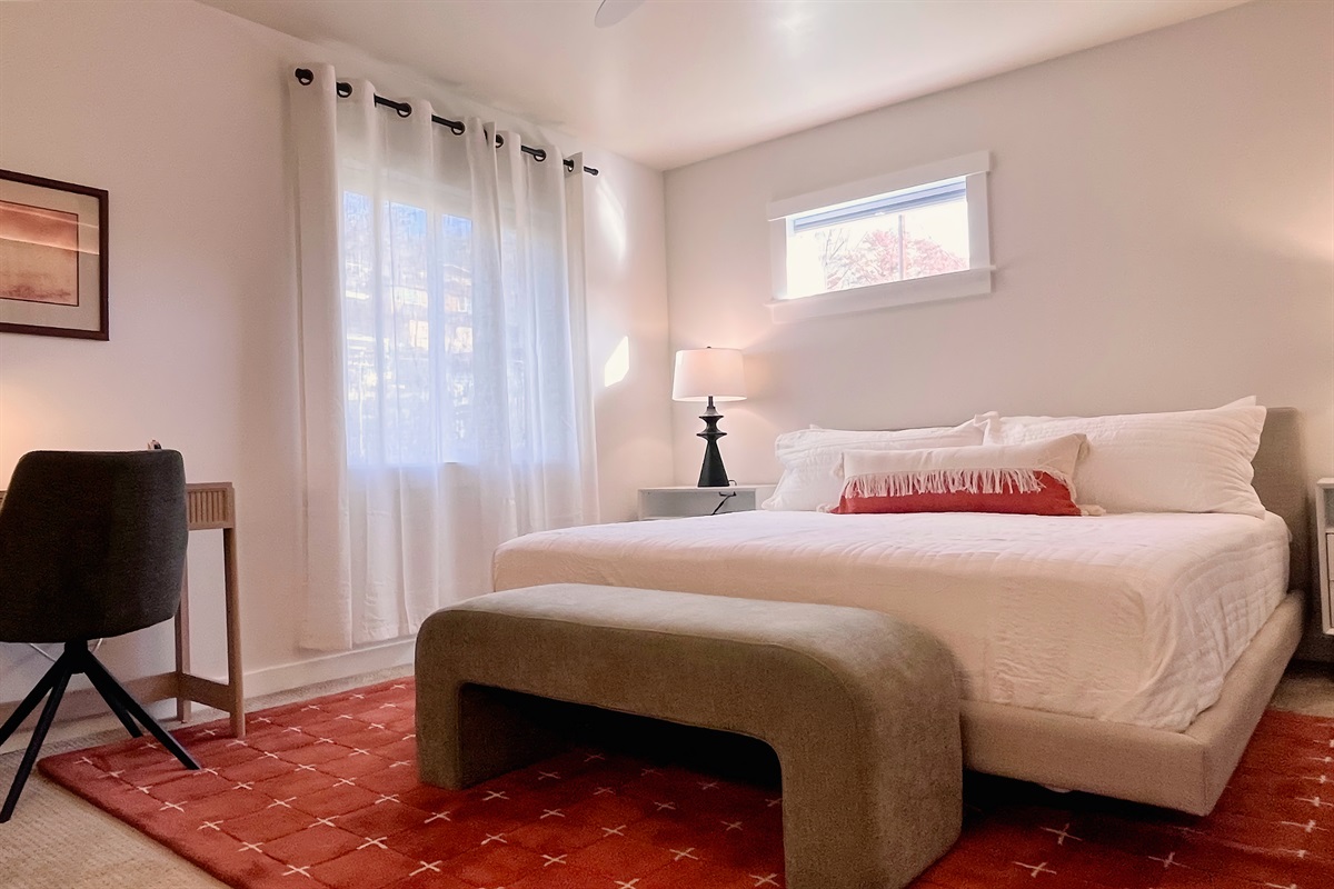 Spacious King bedroom with soft linens, warm light, and a hotel-like feel — plus a desk if you need to plug in.