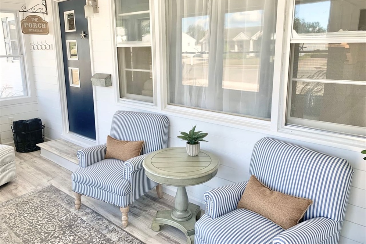 Enjoy a quiet moment in our bright sunroom, featuring comfortable blue-and-white striped armchairs and a classic pedestal side table. This cozy nook is perfect for morning coffee or getting lost in a good book.