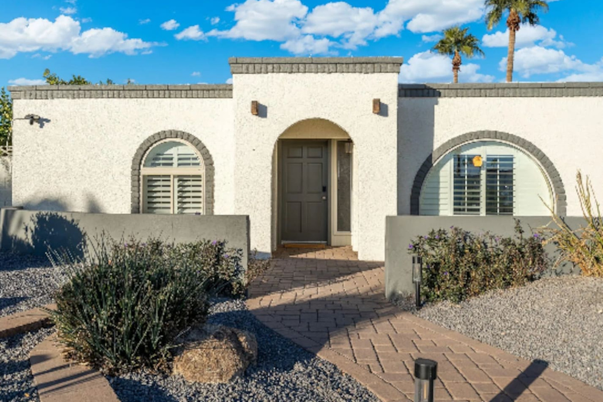 A striking arched entry framed by desert landscaping sets the tone before guests even step inside, low-maintenance and effortlessly stylish.