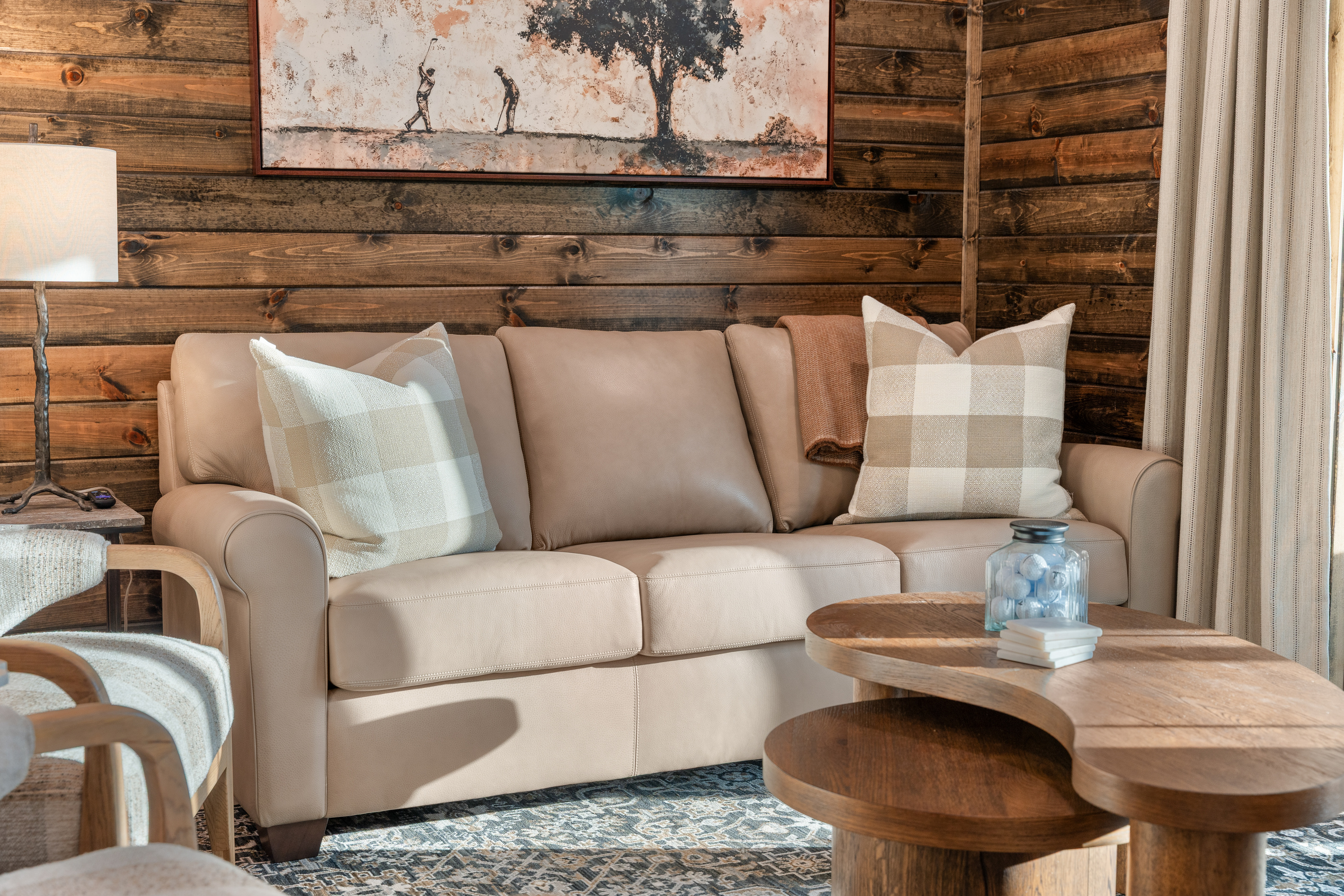 Buffalo-check pillows, a leather sofa, and a curvy oak coffee table set for game night.
