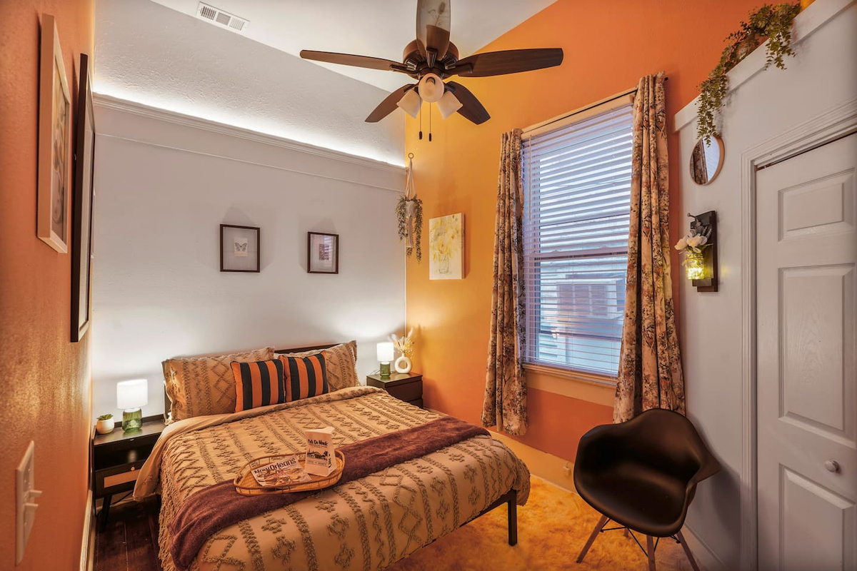 Hanging plants add a vertical touch to the tropical Pink Room with 12-foot ceilings, a queen bed, and a closet.
