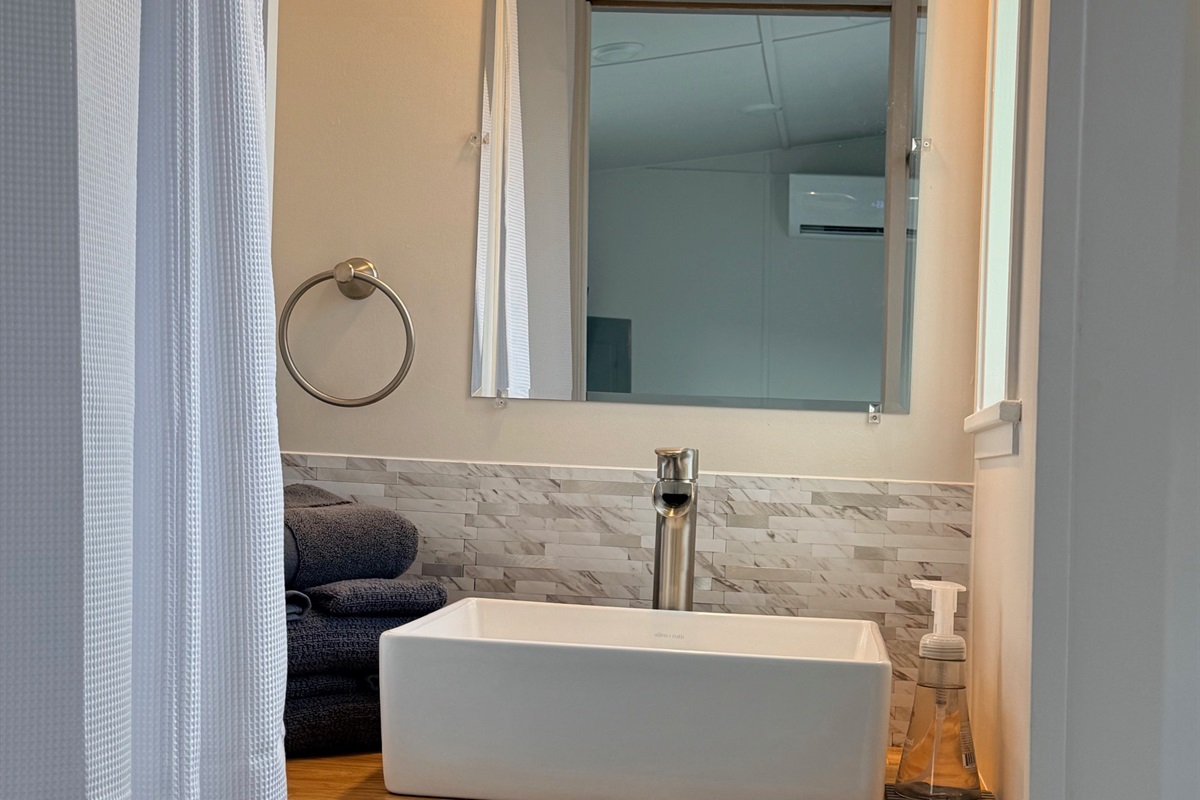 Nice size bathroom with shower, sink and residential toilet