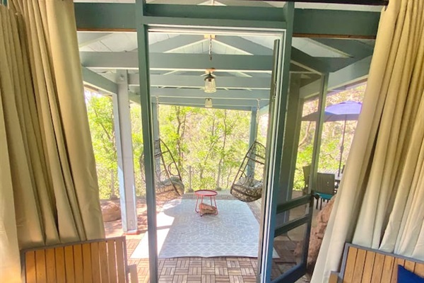 Screen in portion of the gazebo looking to the hanging egg chairs and cliffside.