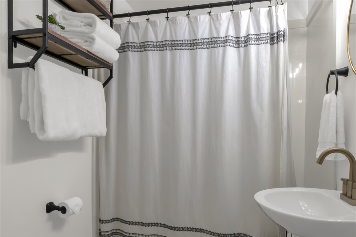 Full bathroom with tub. Added storage for towels and personal items, as well as a wire rack next to the sink.