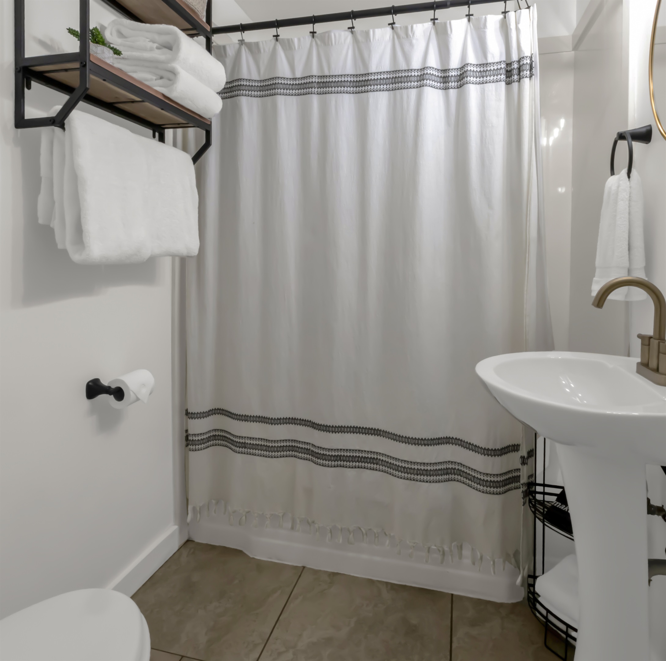 Full bathroom with tub. Added storage for towels and personal items, as well as a wire rack next to the sink.