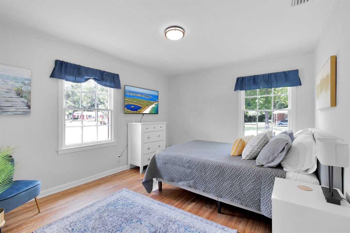 The first bedroom continues the stylish theme with a comfortable queen size bed, a 50" Roku Smart TV, a closet with hangars provided and a dresser for storage.