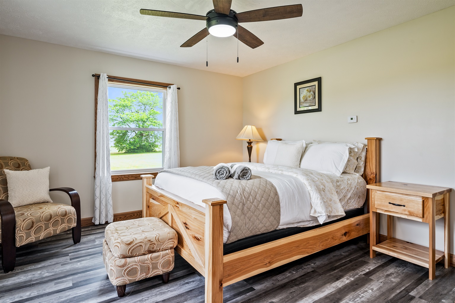 Wake up to natural light and comfort in this beautifully furnished main floor queen bedroom with handcrafted wood furniture and countryside views.