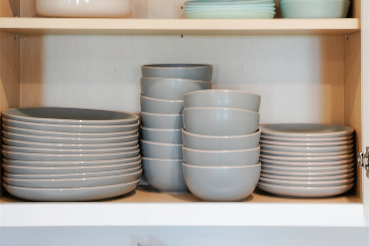Fully stocked kitchen with utensils, plates, bowls, cups, and glasses