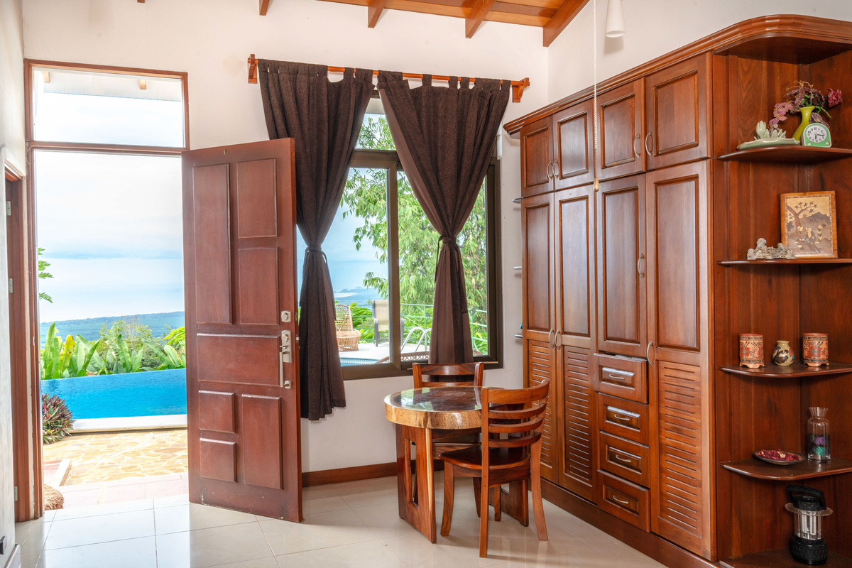 Bedroom sitting area with ocean views, custom wood wardrobe, and private terrace doors