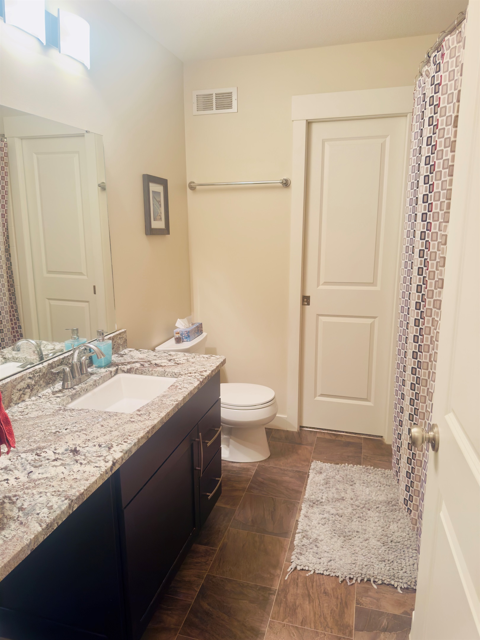 Modern bath with granite vanity, large mirror, and bathtub.