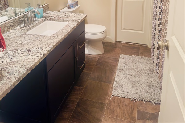 Modern bath with granite vanity, large mirror, and bathtub.