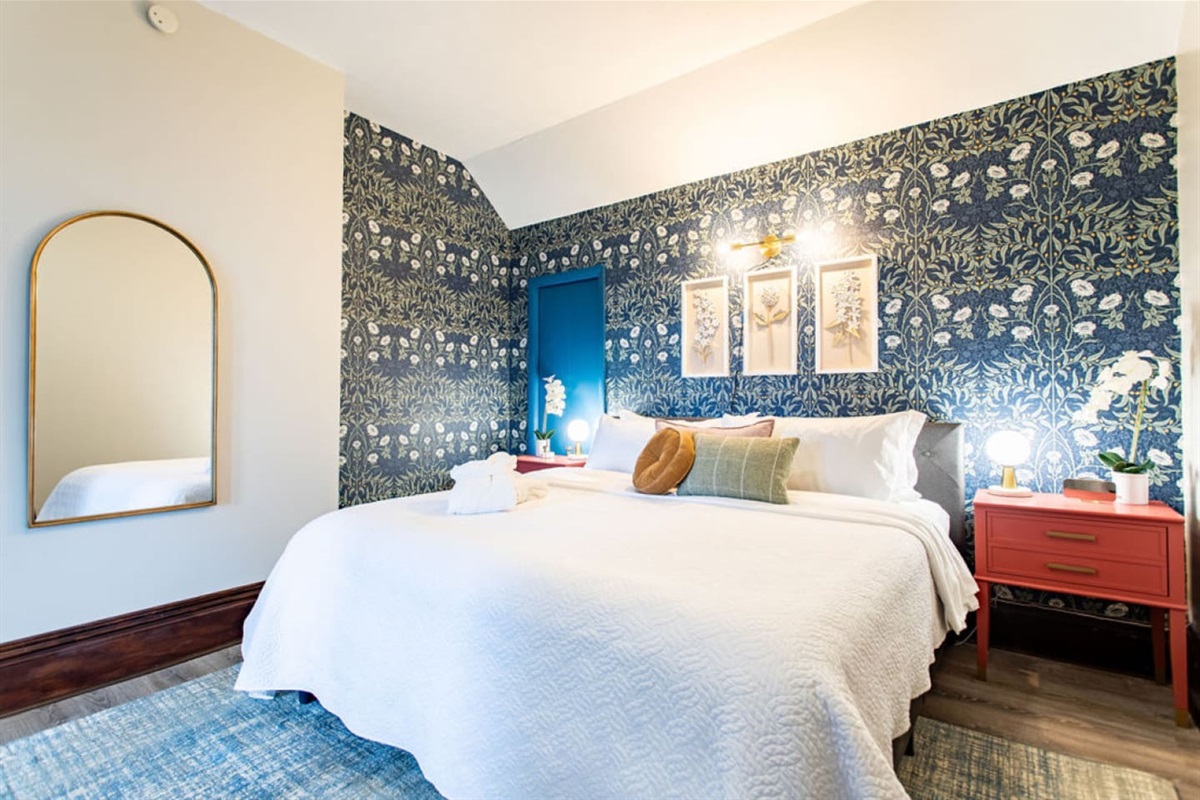 Comfortable, spacious bed with soft linens, complemented by a full-length mirror for added convenience and style.
