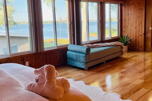 Bedroom with floor-to-ceiling windows offering peasceful views of the lake.