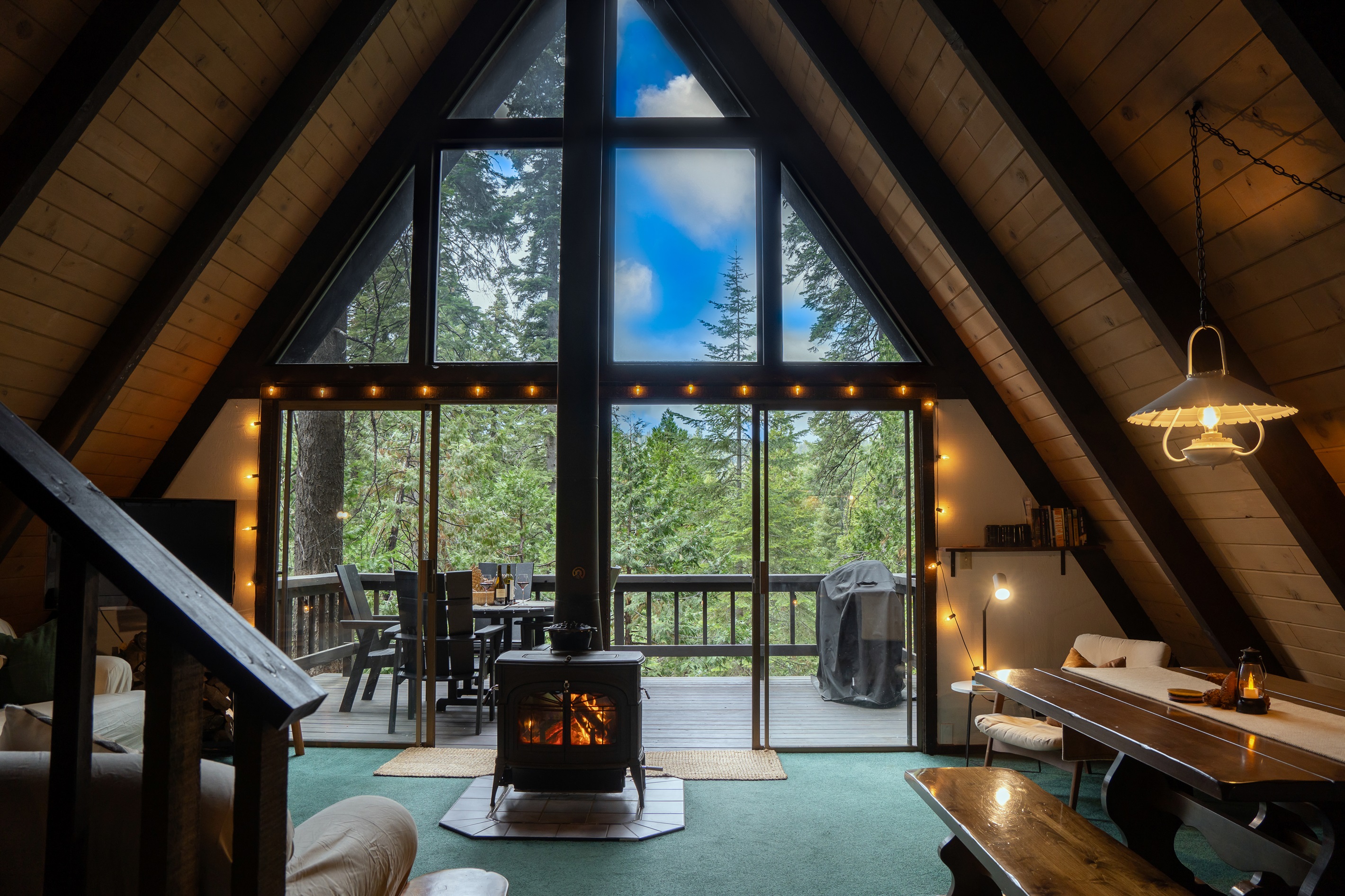 Great room with floor-to-ceiling windows, showcasing sweeping views of the sky and surrounding trees.