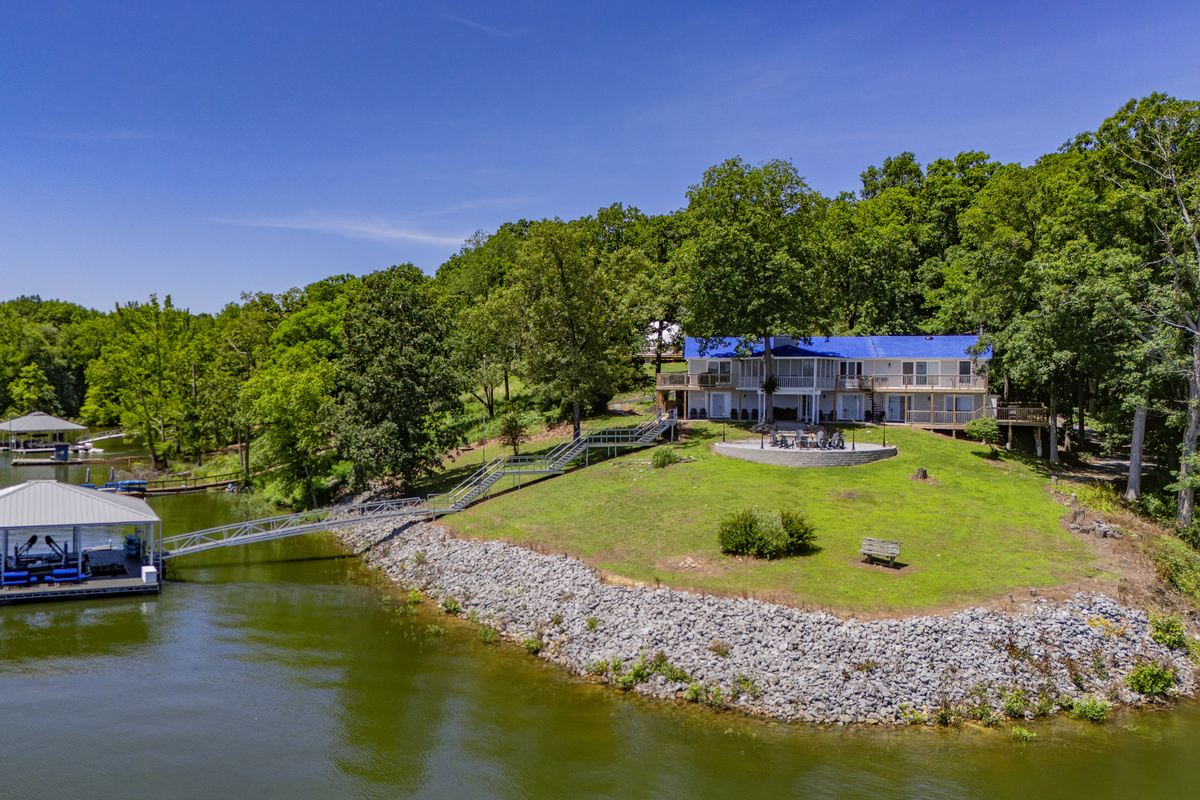 The home sits along a broad waterfront lawn with direct lake access, a firepit, and its own covered dock.