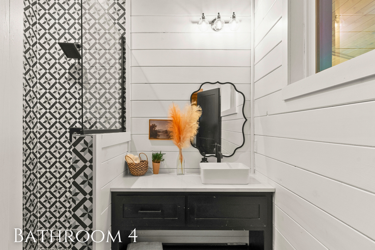 The vanity is fitted with a contemporary vessel sink, and the stylish, uniquely shaped mirror above it adds character to the room.
