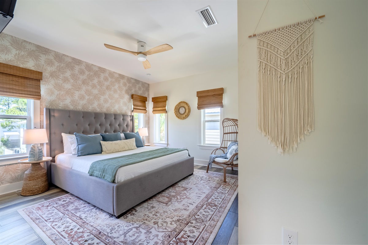 Primary bedroom with king bed, ceiling fan, and cozy seating—designed for comfort and relaxation