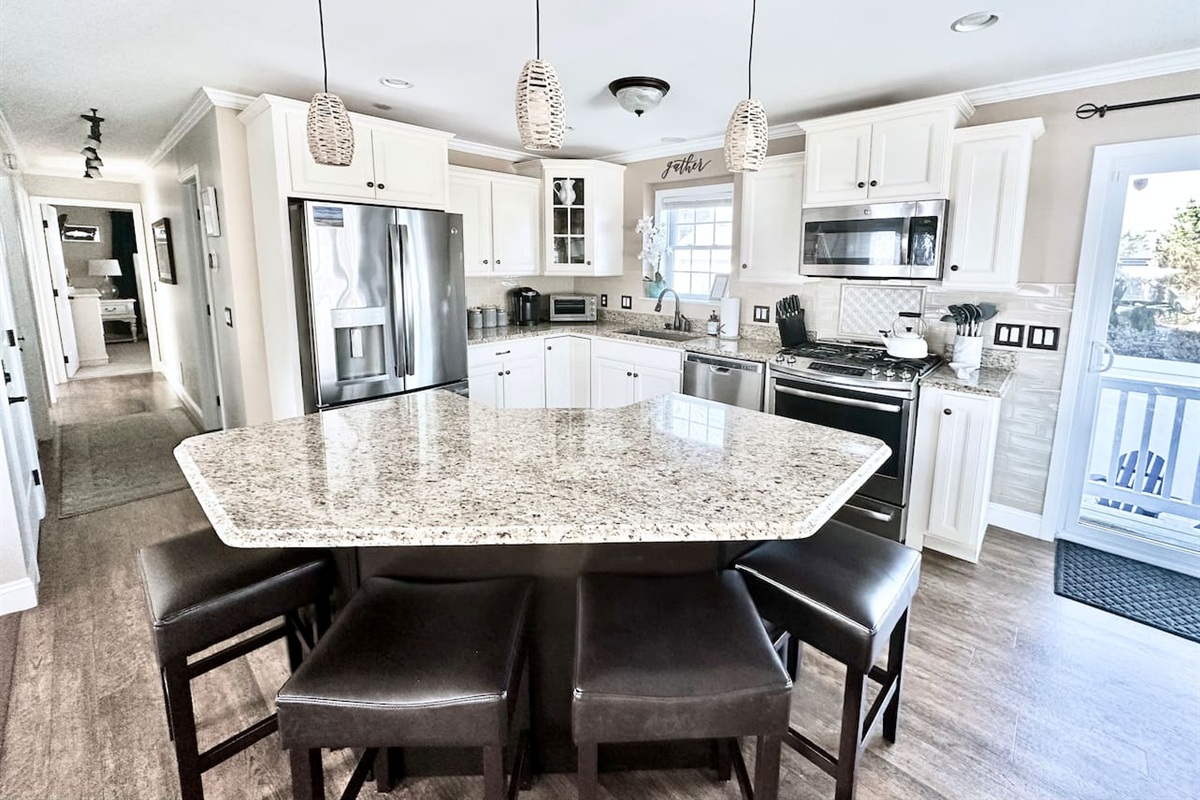 Gather around the spacious granite island, complete with seating for four. This fully equipped kitchen features stainless steel appliances and ample counter space, making it an ideal spot for morning coffee or casual group meals.