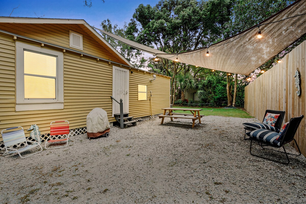 Private rear courtyard in the evening, charcoal grill, shade, seating.