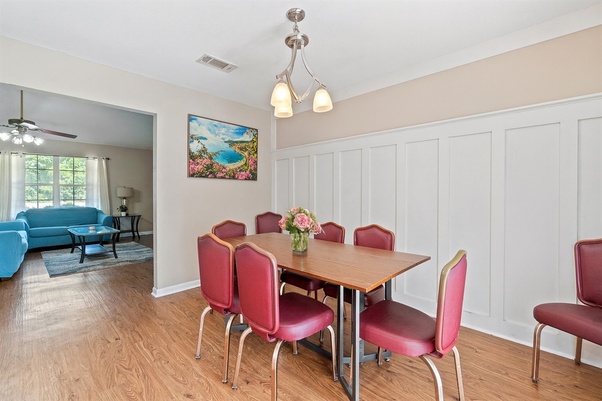 Inviting dining area featuring seating for six, elegant paneling on the wall, and a lovely floral centerpiece—perfect for group meals or game nights.