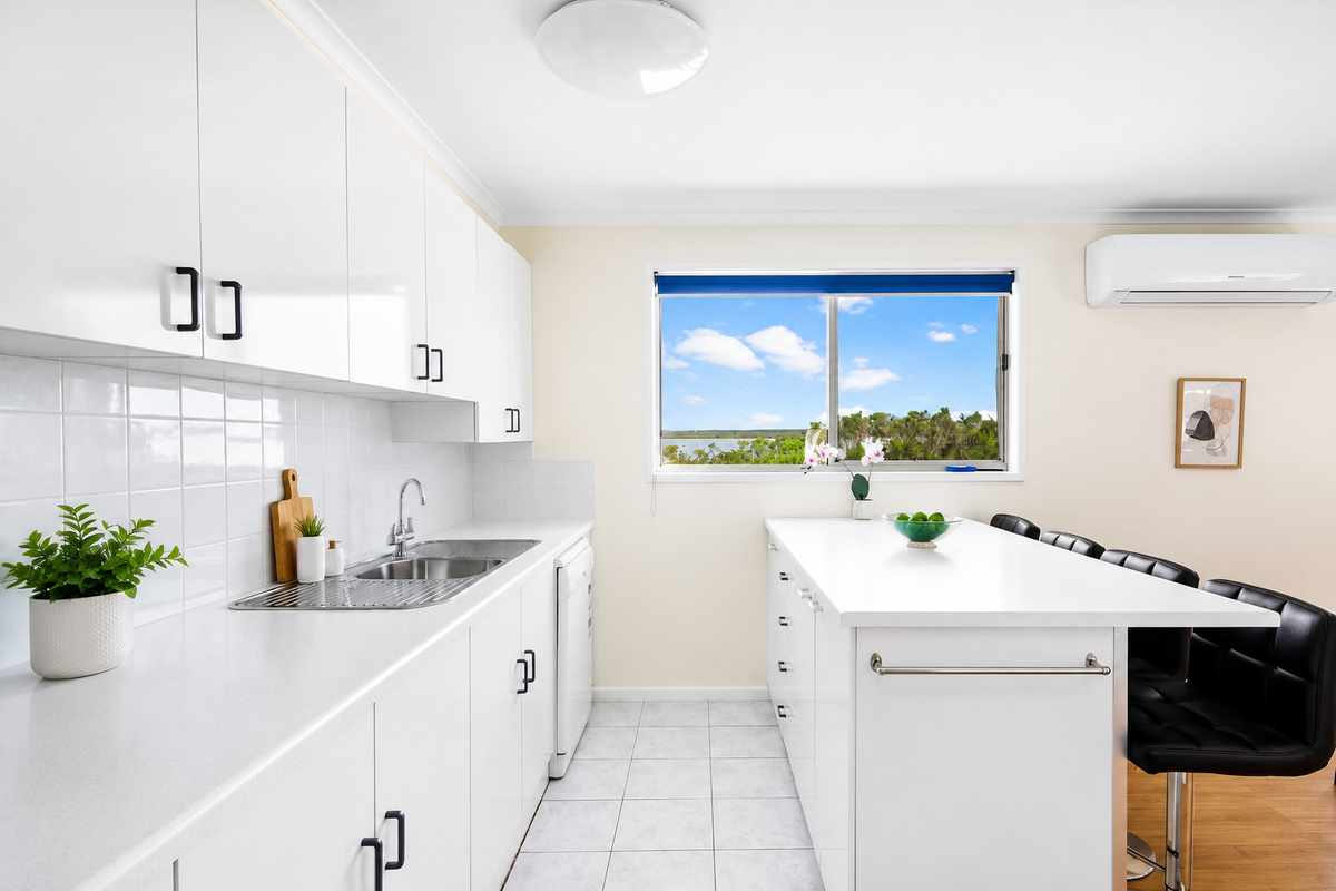 The bright kitchen at Carlenes Getaway includes a generous island bench, coffee station and treetop outlook for easy Loch Sport meals