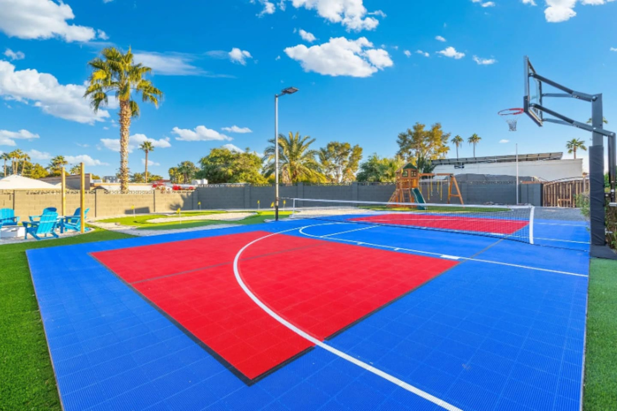 Bold color-blocked courts stretch across the yard, with the playground area visible just past the fence line.
